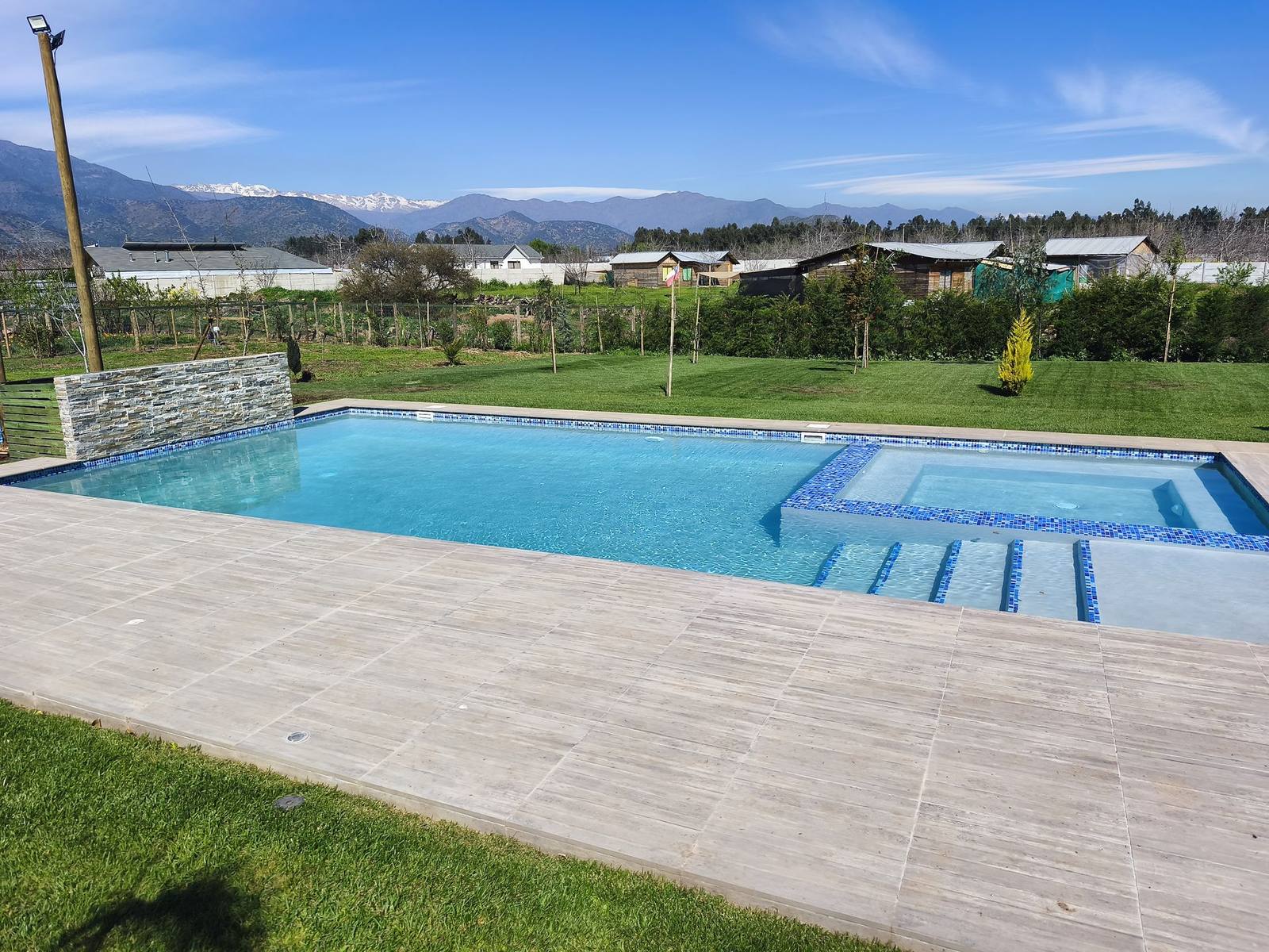 Piscina de hormigón con spa construida por Our Home, con la cordillera de fondo